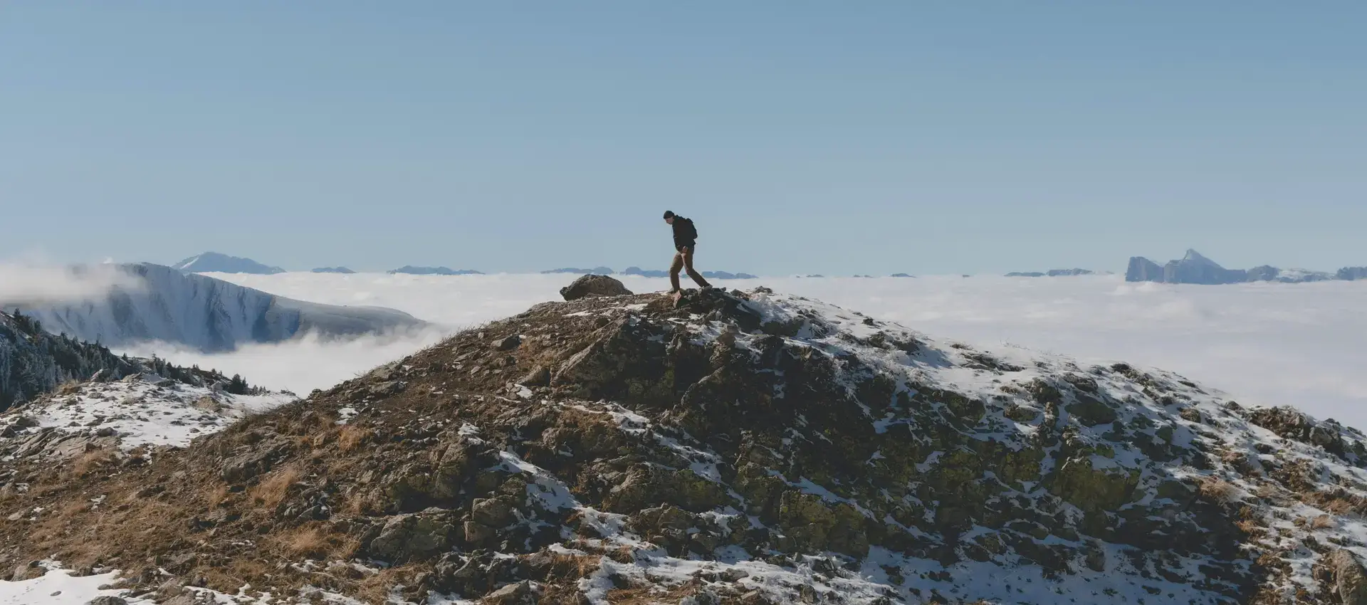 A hiker walking on a snow-covered mountain ridge